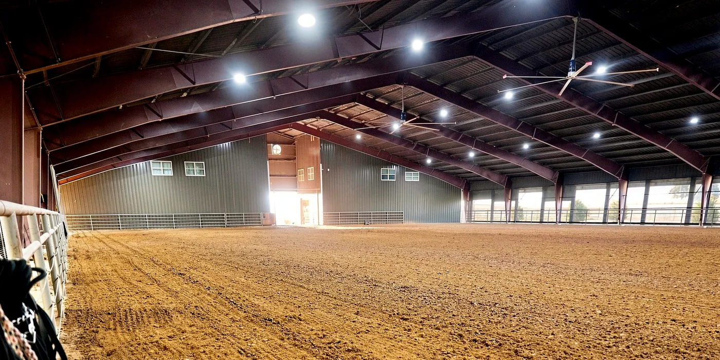 The covered arena at Franklin Farm, with sand footing, overhead fans, and open sides along one wall.