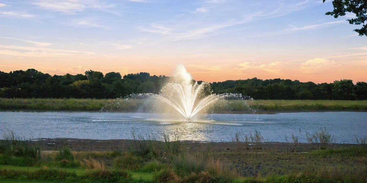 A fountain playing on the pond at Franklin Farm at sunset.